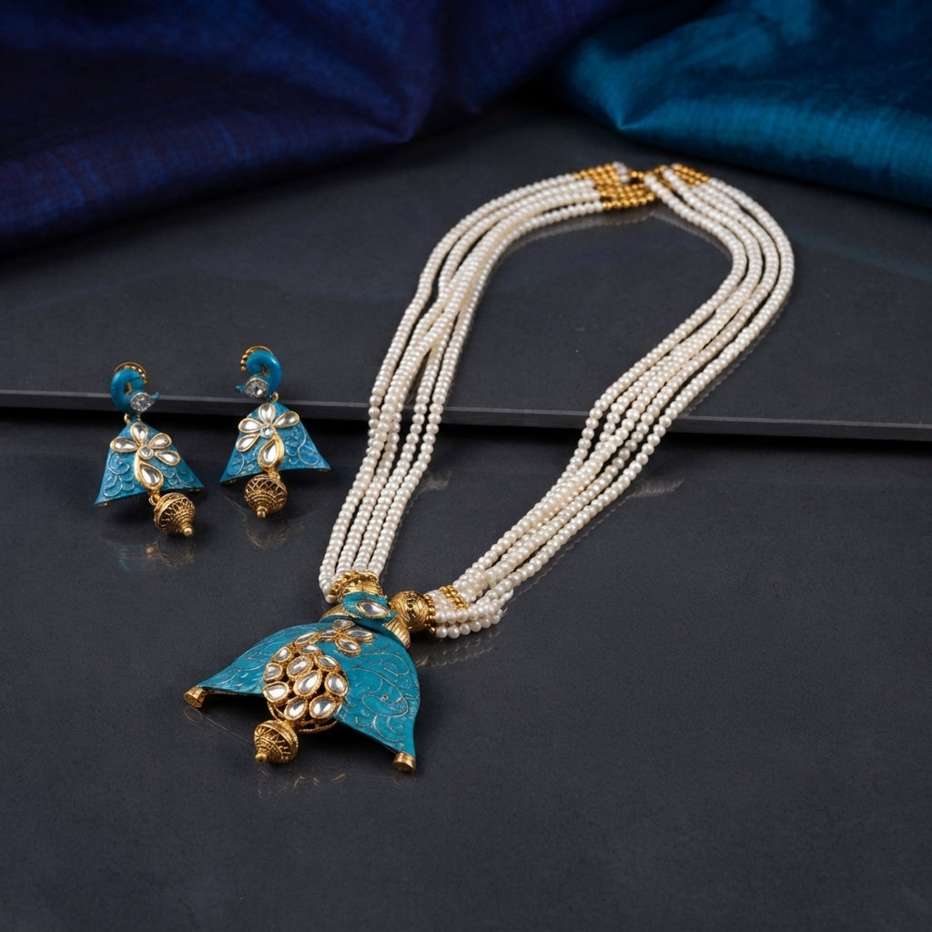 Gold Teal Meenakari Kundan Pearl Jhumka Pendant Necklace Earrings Set on dark grey mirror surface with teal blue silk fabric backdrop showing 6-strand white seed pearl necklace with gold granulation barrel spacers and large teal meenakari enamel triangular pendant with kundan polki CZ floral cluster gold scroll engraving and mini jhumka bell drop alongside matching teal meenakari jhumka earrings with mirror reflections below