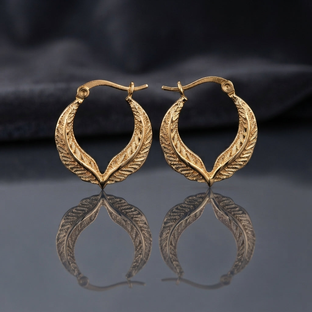 Gold Textured Feather Leaf Twist Teardrop Hoop Earrings pair standing upright on dark mirror surface with charcoal slate satin backdrop showing 22K antique gold-tone pair with two herringbone feather-engraved bands twisting around each other in pointed teardrop flame silhouette with hinged latch-back closure and sharp mirror reflection below