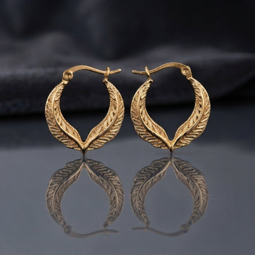 Gold Textured Feather Leaf Twist Teardrop Hoop Earrings pair standing upright on dark mirror surface with charcoal slate satin backdrop showing 22K antique gold-tone pair with two herringbone feather-engraved bands twisting around each other in pointed teardrop flame silhouette with hinged latch-back closure and sharp mirror reflection below