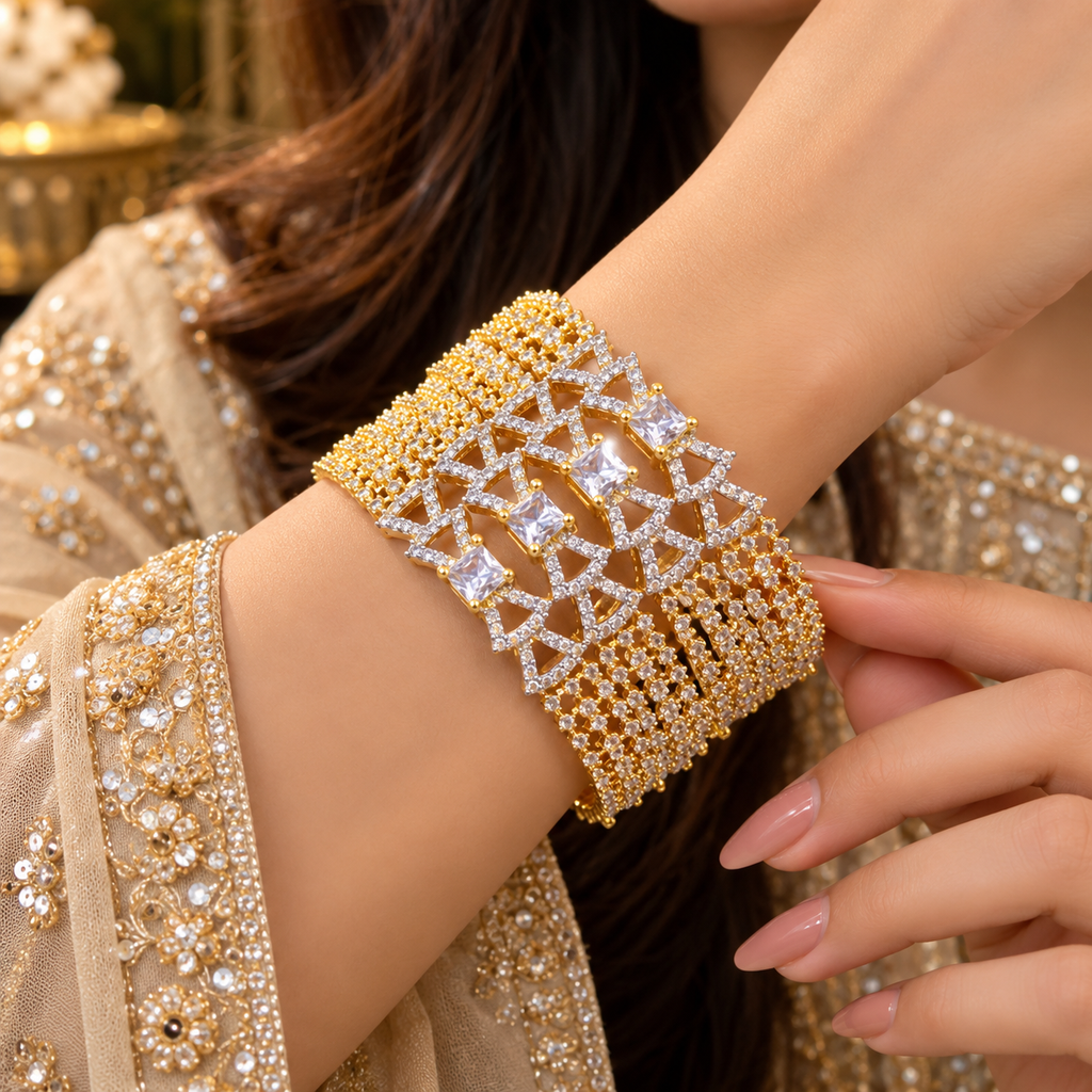 Model wearing four stacked gold-tone AD bangles with square clear centres, angular openwork frames and small clear-accent lattice details.