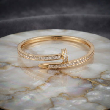 Gold-tone baguette CZ nail bypass bangle with channel-set stones and pointed tip