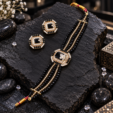 Gold-tone multi-row black bead choker with clear-accent strands, a geometric black butterfly-detail centrepiece and matching earrings.