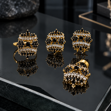 Gold-tone matching earrings, ring and locket with black floral clusters, round centres and two curved rows of clear accents.