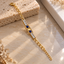 Gold-tone oval-link bracelet with a rectangular butterfly centre panel, two round dark-blue accents and rectangular clear-accent rows on both sides.