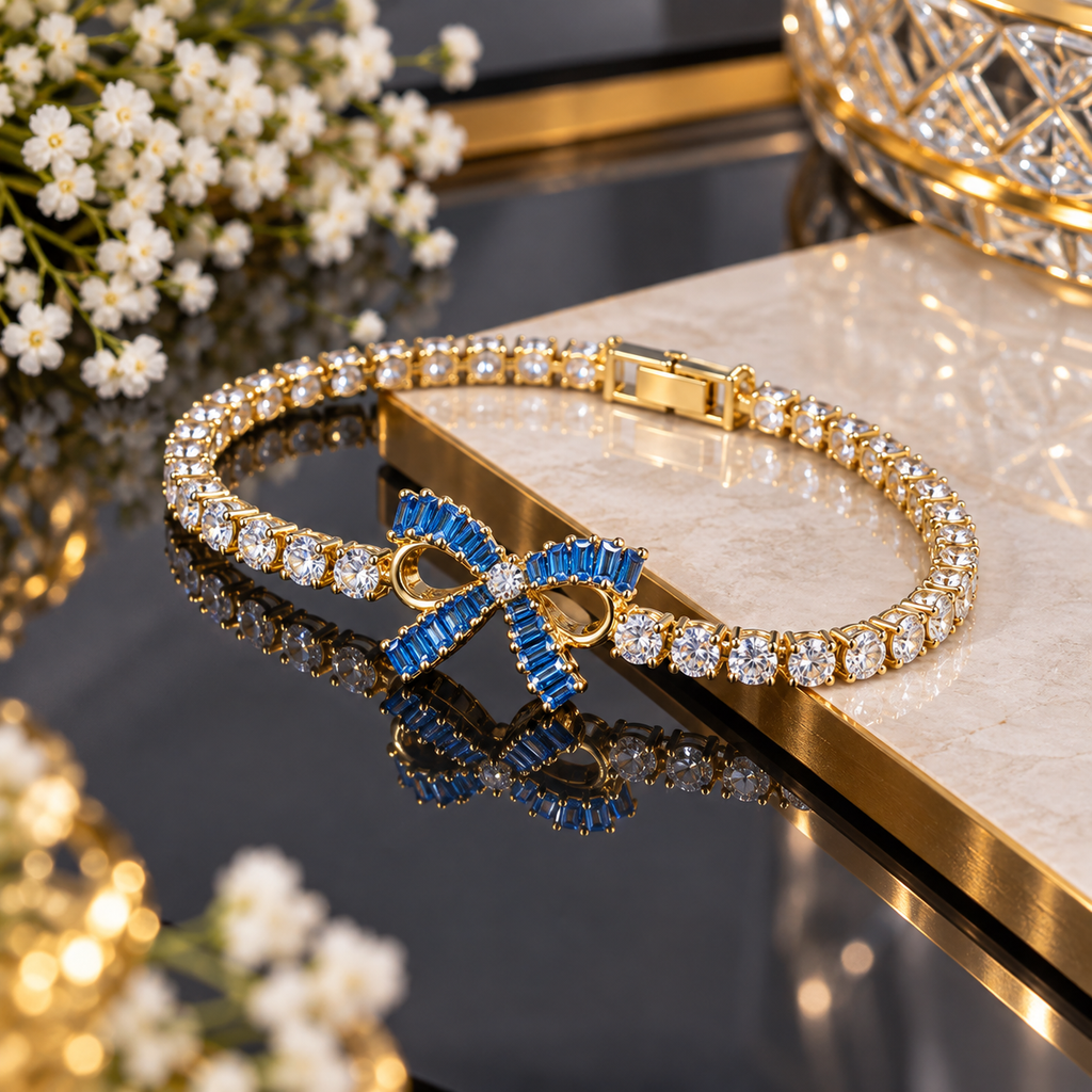 Gold-tone bracelet with round clear-accent links and a blue rectangular-accent bow centre with open-loop detailing.