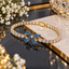 Gold-tone bracelet with round clear-accent links and a blue rectangular-accent bow centre with open-loop detailing.