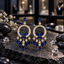 Pair of gold-tone circle chandelier earrings with blue butterfly details, clear sparkling accents and graduated blue teardrop drops.