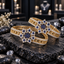 Pair of gold-tone openwork bangles with dark blue floral clusters and clear accent borders, displayed on dark slate.