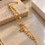 Gold-tone double-chain bracelet with elongated oval links, four ivory-white pearl-look beads, a textured butterfly charm and a round clear accent.
