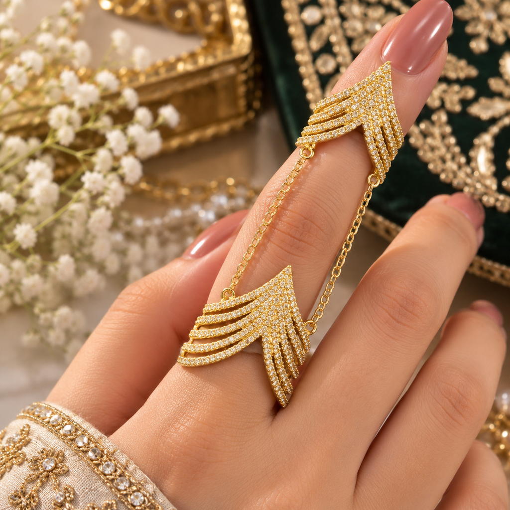 Gold-tone chain-linked double ring worn on one finger, showing two layered chevron sections with clear accents.