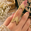 Gold-tone chain-linked double ring worn on one finger, showing two layered chevron sections with clear accents.