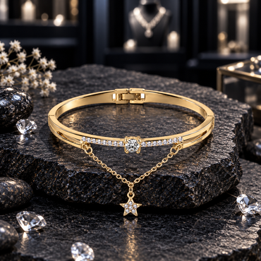 Gold-tone bangle with clear accents across the front, a round clear centre detail and a draped chain with a sparkling five-point star charm.