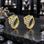 Pair of gold-tone hoop earrings with openwork crown-like scroll detailing beside a curved row of round clear sparkling accents.