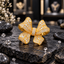 Gold-tone ribbon bow statement ring with raised folded loops, curved ribbon tails, a centre wrap and mixed-size clear-looking accents.