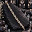 Gold-tone bracelet with repeating intertwined open loops, rows of clear rectangular accents and small round-accent connecting details.