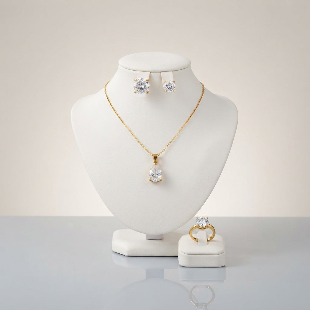 Gold-tone set displayed with a clear-stone pendant necklace, stud earrings, and a matching ring.
