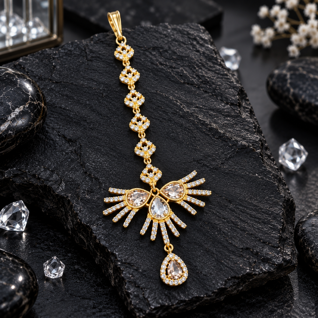 Gold-tone bindia with clear-accent upper links, three teardrop-shaped centre accents, radiating fan-style bars and a hanging clear teardrop halo drop.