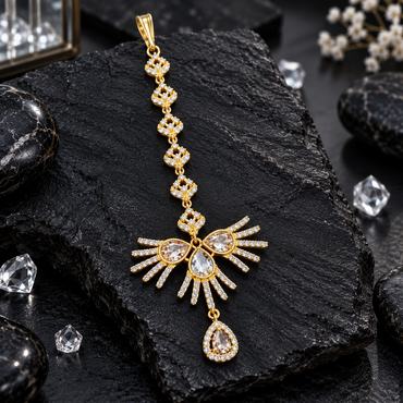 Gold-tone bindia with clear-accent upper links, three teardrop-shaped centre accents, radiating fan-style bars and a hanging clear teardrop halo drop.