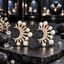 Pair of gold-tone clear-accent crescent earrings with radiating rectangular details and cream-white pearl-look beads in varied sizes.