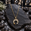 Gold-tone chain necklace with a downward-opening crescent pendant, clear accents along the curve and yellow and clear triangular tips, displayed on dark slate.