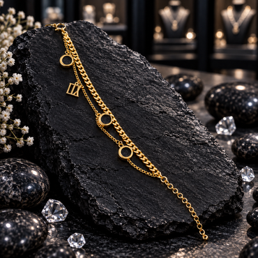 Gold-tone double chain bracelet with a curb-style strand, a fine linked strand, three open circles, a rectangular openwork charm and round-link tail.