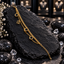 Gold-tone double chain bracelet with a curb-style strand, a fine linked strand, three open circles, a rectangular openwork charm and round-link tail.