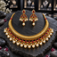 Gold-tone embossed collar-style necklace with red teardrop accents and cream pearl-look fringe, alongside matching red chandelier earrings.