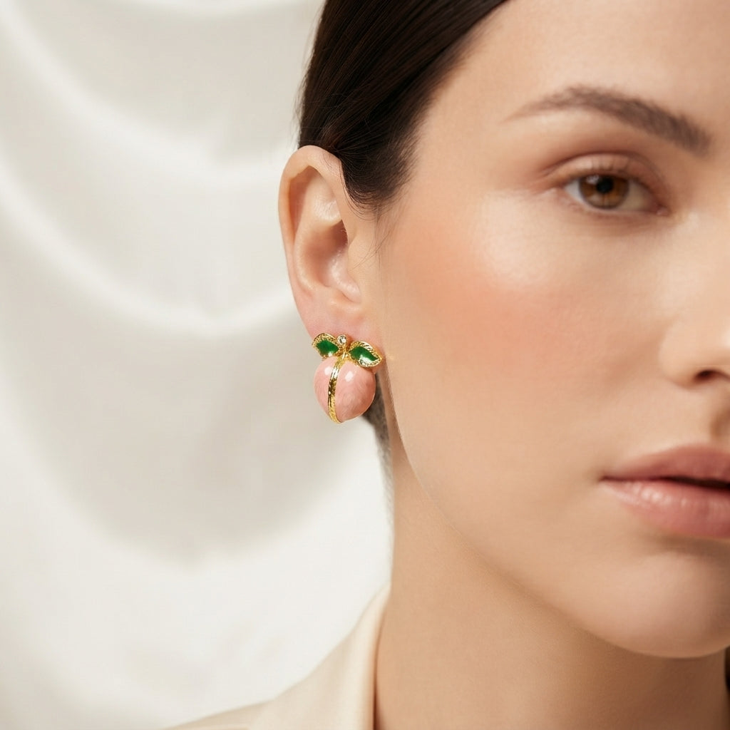 Gold-Tone Enamel Fruit Peach Stud Earrings in blue enamel pair displayed on dark mirror surface with black silk drape backdrop showing round blue enamel peach form with gold-tone ribbed engraved seam divider and two green enamel leaves at top with mirror reflection below