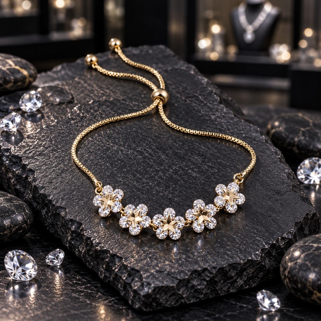 Gold-tone chain bracelet with five clear-petal flower motifs, star-shaped centres, a slider-style bead and two round-ended chain tails, displayed on dark slate.