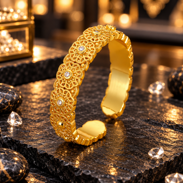 Gold-tone open cuff bracelet with repeating flower-shaped filigree motifs, round clear centre accents, bead-like details and scalloped edges.