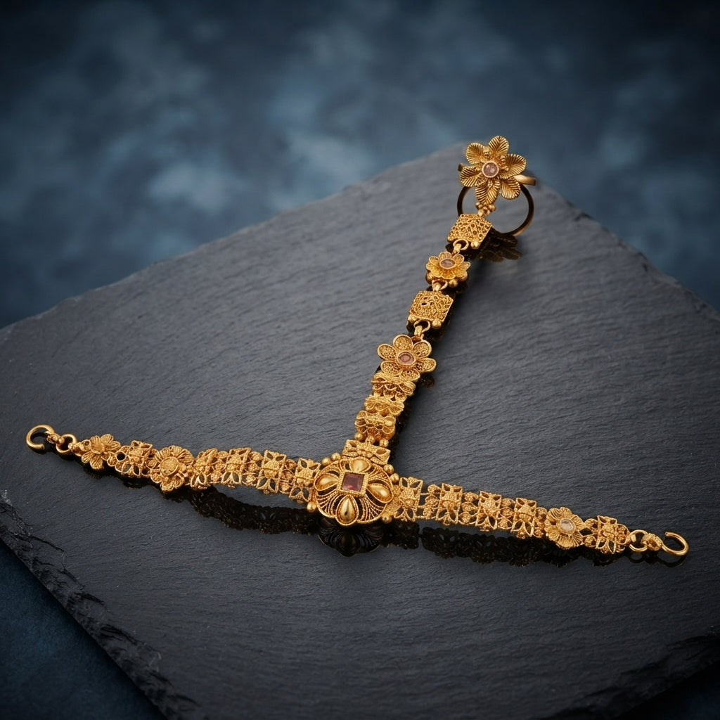 Gold-tone floral hathphool hand harness with an ornate wrist bracelet and linked finger ring, displayed on a dark surface.