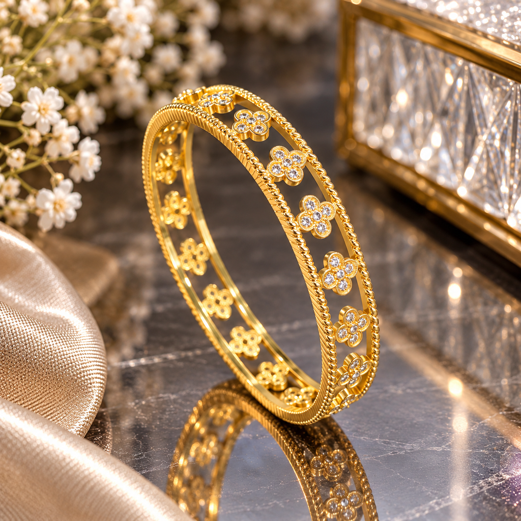 Gold-tone openwork bangle with repeating four-petal clear-accent flowers between two rope-style textured borders.