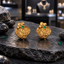 Gold-tone Rajwari earrings with raised diagonal leafy branches, curling scrollwork, pointed lower edges and round green accents near the top.