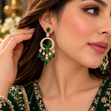 Gold-tone green butterfly circle chandelier earrings with clear sparkling borders and hanging teardrops, worn with an embroidered outfit.