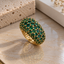 Gold-tone domed cluster ring with round green faceted accents and bead-like setting details.