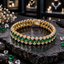 Gold-tone linked bracelet with diagonal green rectangular accents, round clear accents along both borders and a rectangular back closure section on dark slate.