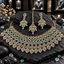Gold-tone AD set with a broad green rectangular-accent and leaf-fringe necklace, matching green-top earrings and an openwork leaf-motif bindia.