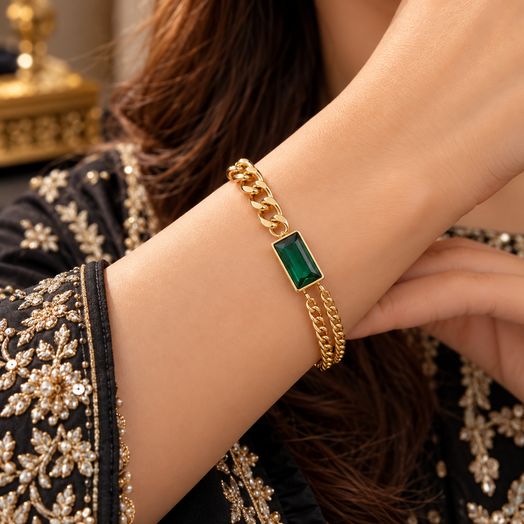 Gold-tone green rectangular centre bracelet worn on a model’s wrist, showing chunky chain links on one side and two finer parallel chains on the other.