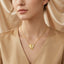 Gold-Tone Half CZ Pavé Rope Twist Heart Pendant Necklace worn by model on beige background