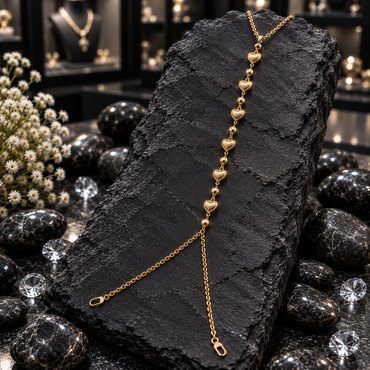 Gold-tone Hand Chain with six bordered heart motifs alternating with round beads, a chain loop at the top and two branching chains below.