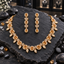 Gold-tone AD-style necklace with honey-gold-coloured oval halo accents and clear-looking leaf drops, alongside matching long teardrop-finish earrings.