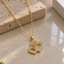 Gold-tone necklace with overlapping large and small open-heart pendants, clear-accent outlines, a smooth bail and a fine linked chain.