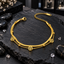 Gold-tone layered bracelet with a flat textured chain, fine link chain, three round openwork tree charms, small beads, lobster-style clasp and extension chain on dark slate.