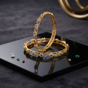 Gold-Tone Multi-Color CZ Floral Scroll Open-Work Slim Bangle Pair displayed upright and flat on black mirror tray with dark grey marble backdrop and scattered ruby emerald and diamond CZ stones showing two matching slim gold bangles with continuous open-work scroll arabesque lattice curved vine links ruby-red CZ center white CZ petal emerald-green CZ floral clusters and fine gold beaded wire border with mirror reflection below