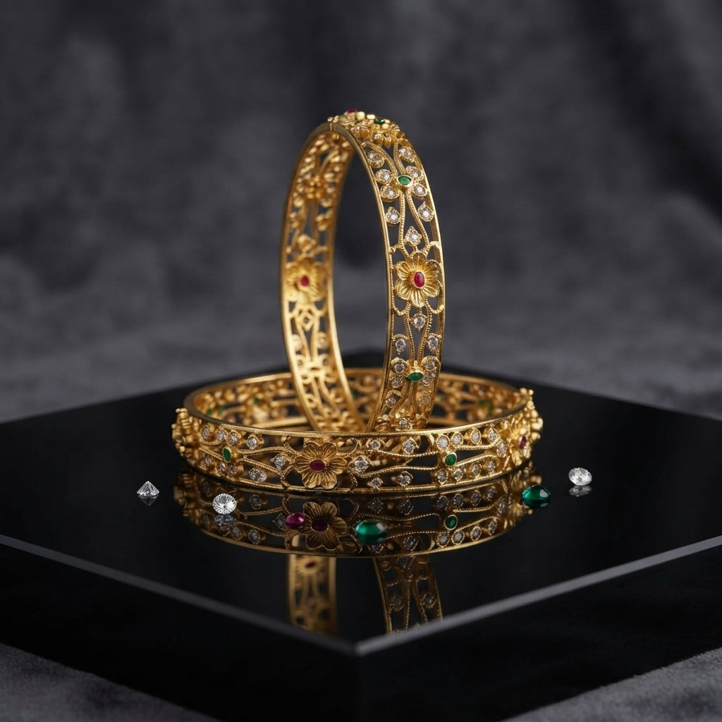 Gold-Tone Multi-Color CZ Scattered Floral Open-Work Filigree Wide Bangle Pair displayed upright and flat on black mirror tray with dark grey marble backdrop showing two matching wide gold bangles with intricate open-work filigree lattice vine branch motifs scattered round white CZ stones large 5-petal ruby-red CZ center daisy flowers and teardrop emerald-green CZ accents with mirror reflection below