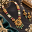 Gold-tone beaded necklace set with floral pendant and matching drop earrings, green and red accents, and ivory-colored strands.