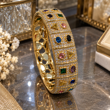 Gold-tone wide bangle with clear-accent panels and multicolor round, oval, square and triangular details.
