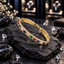 Single gold-tone bangle with blue, green, red, pale pink and purple rectangular accents, clear sparkling details and textured edging.