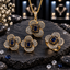 Gold-tone four-petal jewelry set with navy-blue rectangular centres, clear-accent petals, a pendant on an oval-link chain, matching earrings and ring.