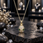 Gold-tone beetle-inspired oval pendant necklace with clear sparkling detailing, two green accents and a matching-tone link chain.